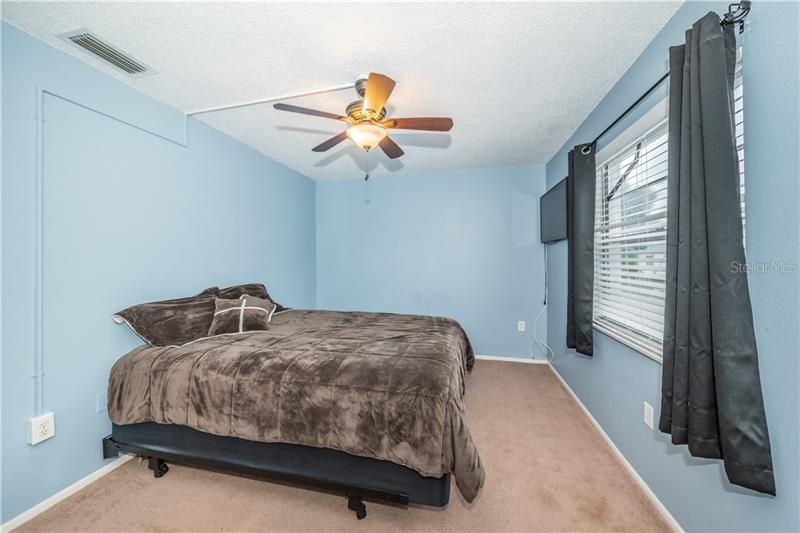 Bedroom with ceiling fan, natural lighting