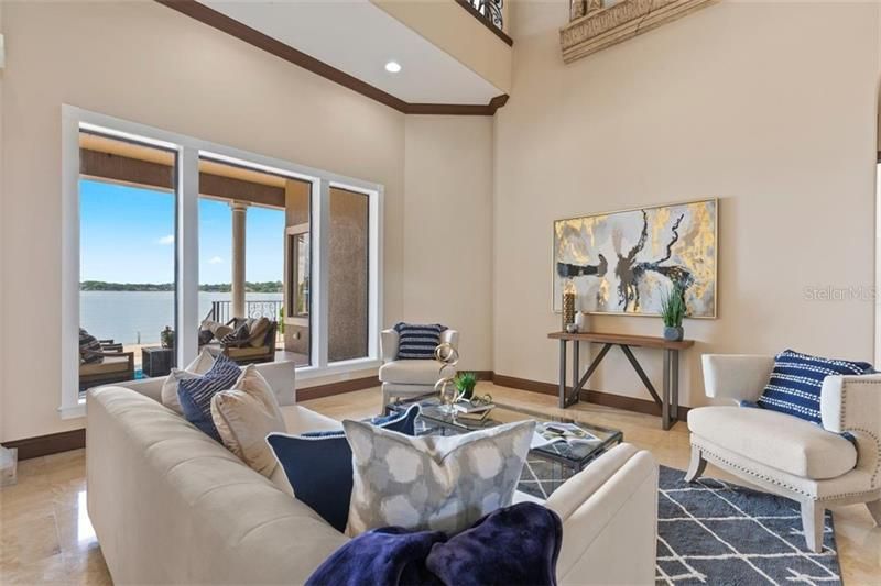 The palatial living room with a soaring ceiling and a stunning lake view.