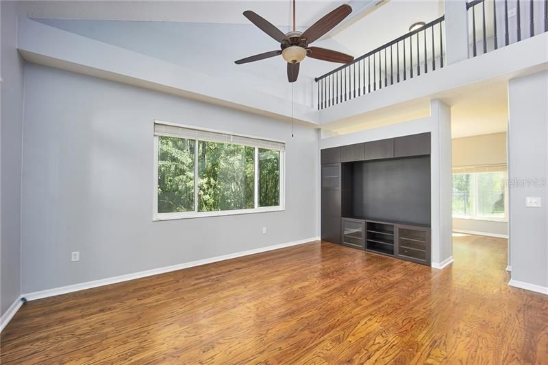 Formal living room with upgraded wood floors & built in entertainment area, elegant balcony overlook from loft above!