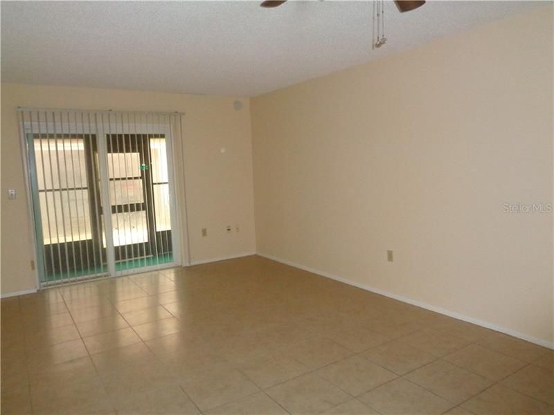 Fully Tiled living room with sliding glass doors to vinyl enclosed porch