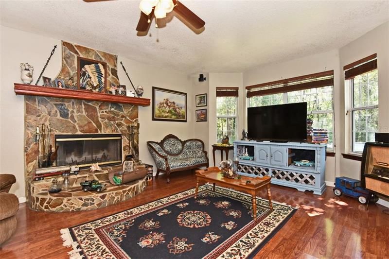 Living room with beautiful laminate floors, wood burning fireplace & bay window that lets the natural light in!