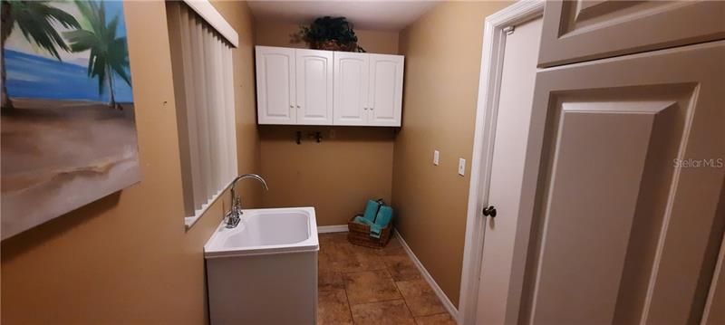 indoor laundry room with wet sink and door to garage