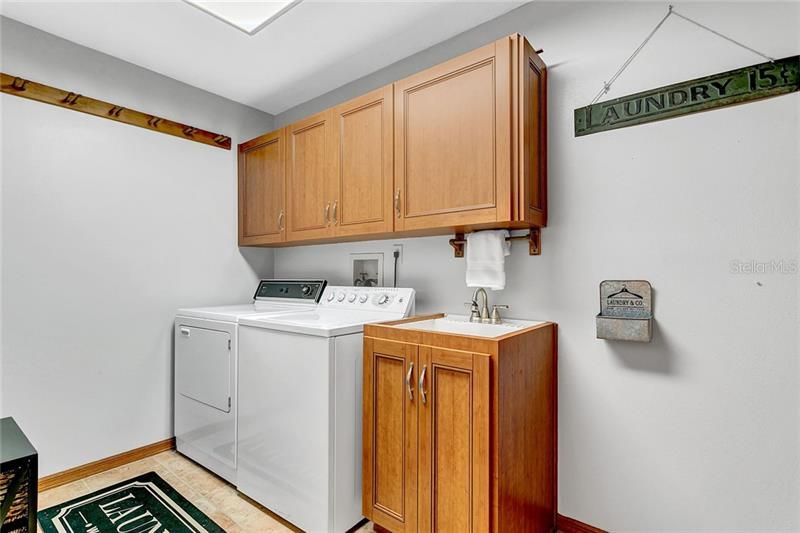 Indoor Laundry Offers Sink and Storage Cabinets and a Brand New Washer