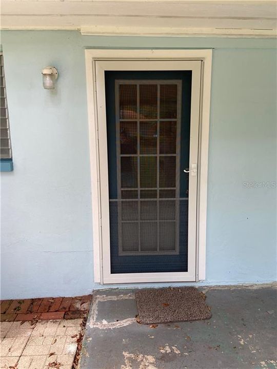 Screened storm door on side of house under carport