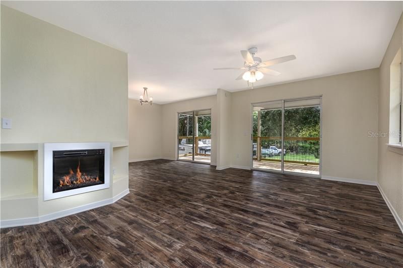 Inside entrance with electric fireplace, beautiful vinyl planking floors & sliders to the beautiful, private property!