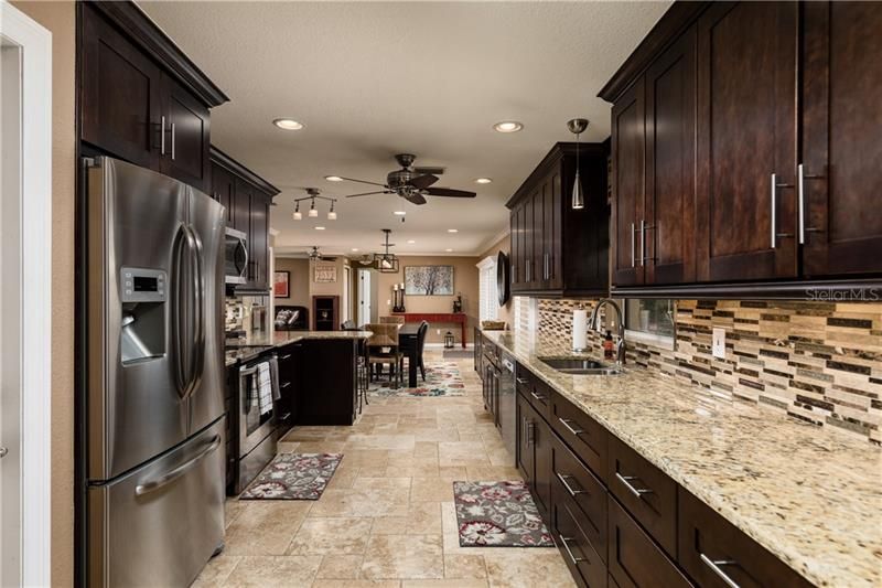 Galley kitchen with lots of counter space for prep work and stainless steel appliances. Kitchen sink overlooks the pool area, too!