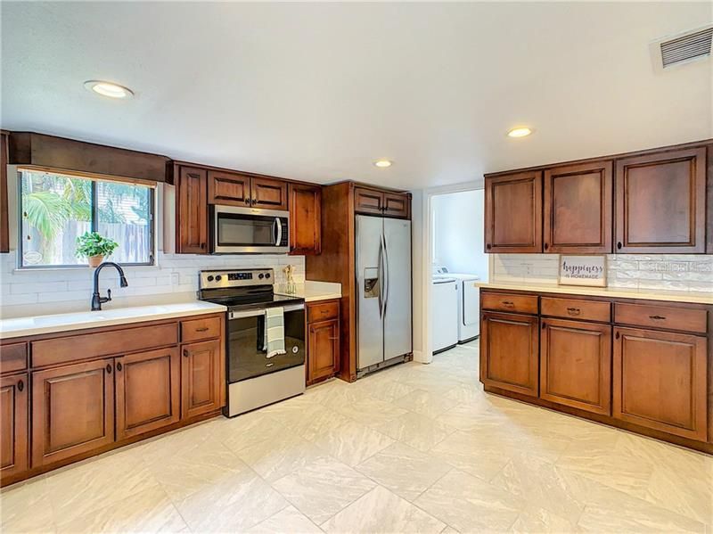 Kitchen has new appliances, Corian counter tops with plenty of work space, tile back splash, lots of upper & lower cabinets, stainless steel appliances and a large pantry.