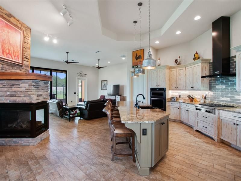 Open concept kitchen with view of family room & 3 sided fireplace.