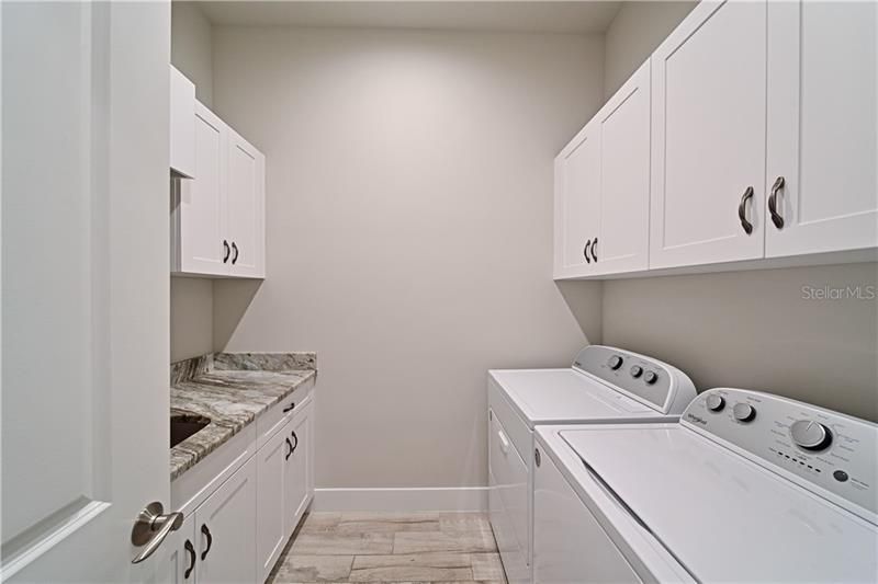 Seperate Laundry Room with tons of storage space, laundry sink, hanging clothes bar, and folding counter.