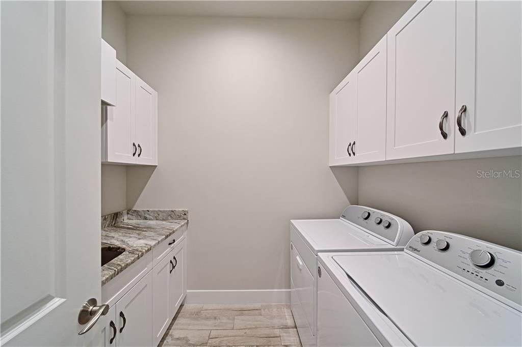 Seperate Laundry Room with tons of storage space, laundry sink, hanging clothes bar, and folding counter.