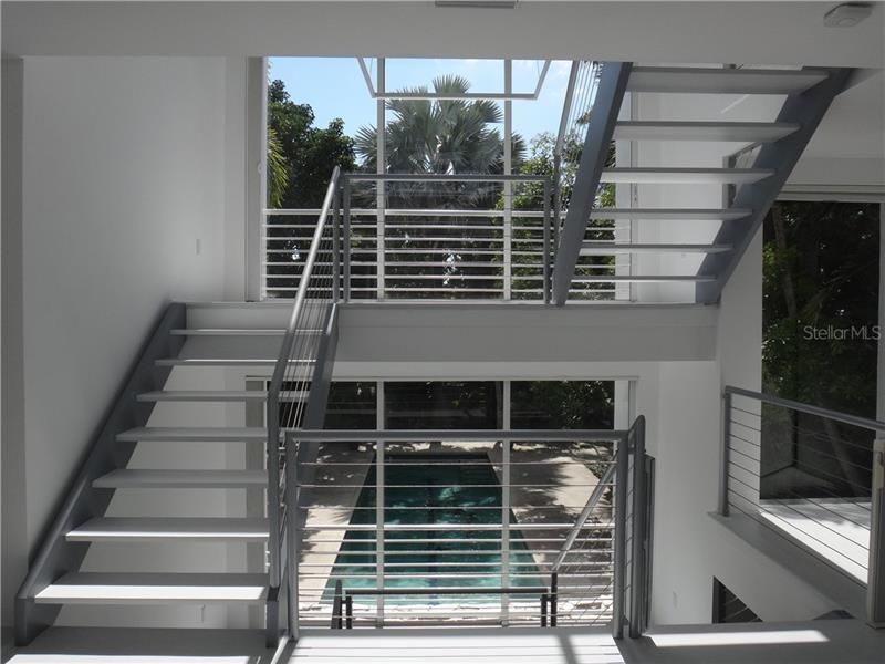 Stair case leading to second level and with view of the pool