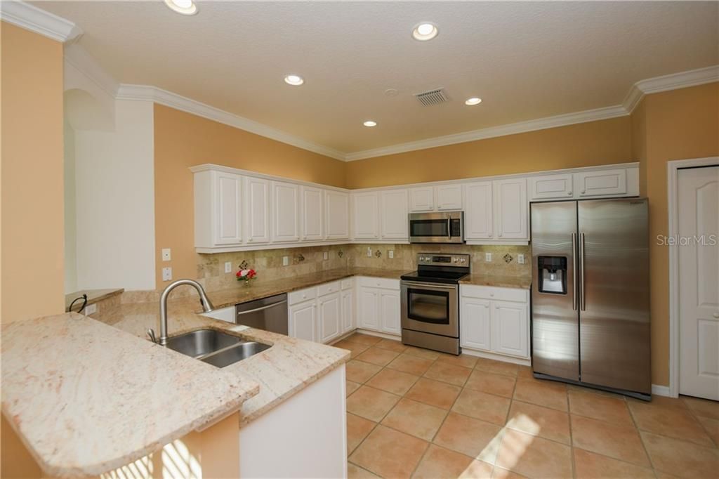 Spacious Kitchen with Granite tops, under cabinet lighting and newer Stainless appliances