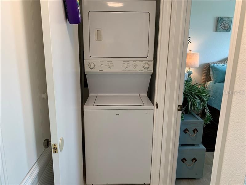 Stackable washer and dryer in closet right outside master bedroom.