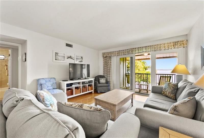 Roomy living room with flat screen TV, pull out couch, loveseat and gorgeous views of Anna Maria Sound.  Sliders are current hurricane code.