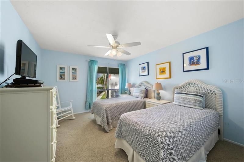 Spacious guest room with flat screen TV, ample closet and cheerful beach decor.