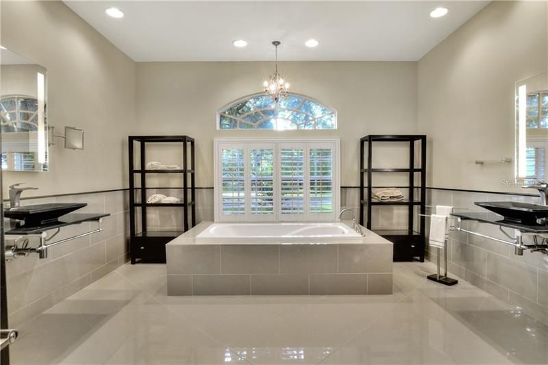 Glamorous master bathroom with dual wall mounted sinks.  Porcelain tile floors and Plantation Shutters.
