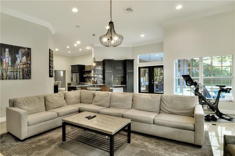 Family room with porcelain tile floors, crown molding, volume ceilings and contemporary lighting.