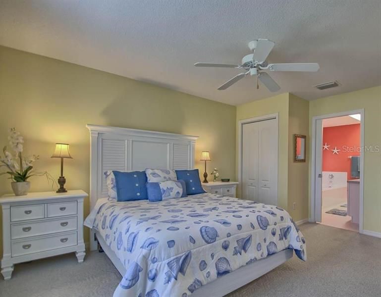 LIGHT AND BRIGHT MASTER BEDROOM WITH CARPET FLOORING AND CEILING FAN.