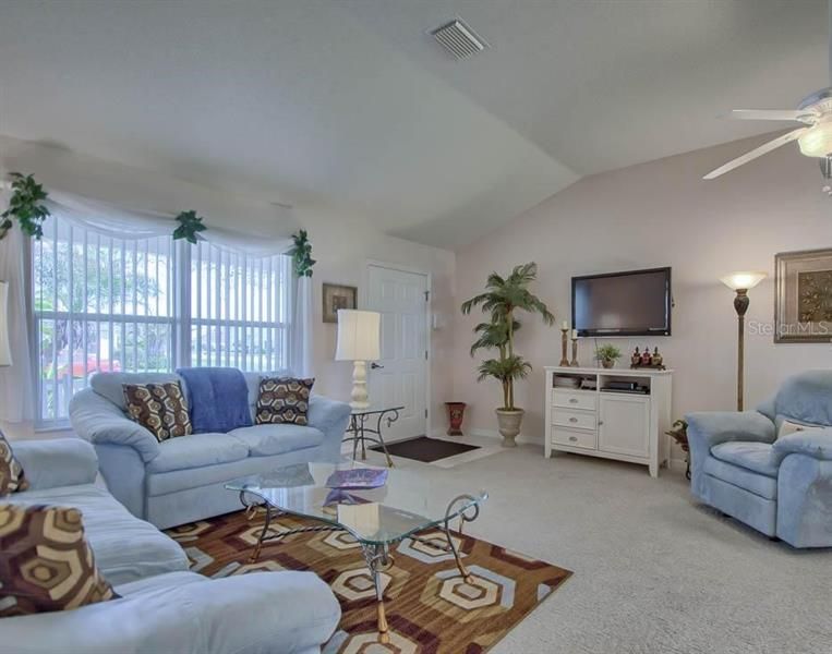 LIVING ROOM WITH VAULTED CEILINGS, CEILNG FAN AND CARPET FLOORING.