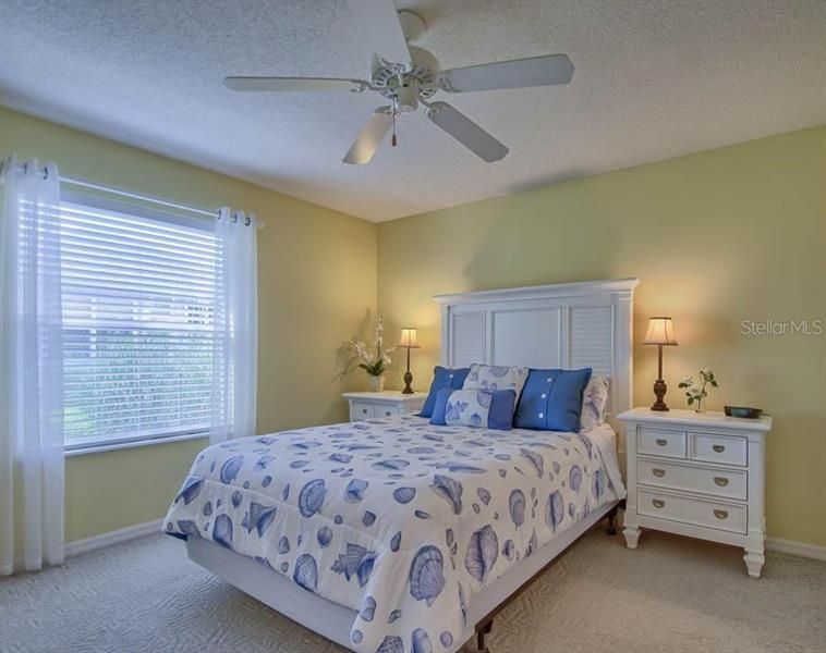 LIGHT AND BRIGHT MASTER BEDROOM WITH CARPET FLOORING AND CEILING FAN.
