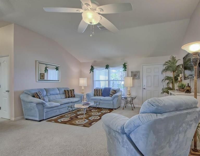 LIVING ROOM WITH VAULTED CEILINGS, CEILNG FAN AND CARPET FLOORING.