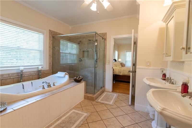 The Owner's Spa/Bathroom Retreat features a jetted tub and separate shower, pedestal sinks, and tons of storage. A linen closet is located just inside the bathroom behind the bathroom door. It is seen near the right side of this photo just beyond the sink.