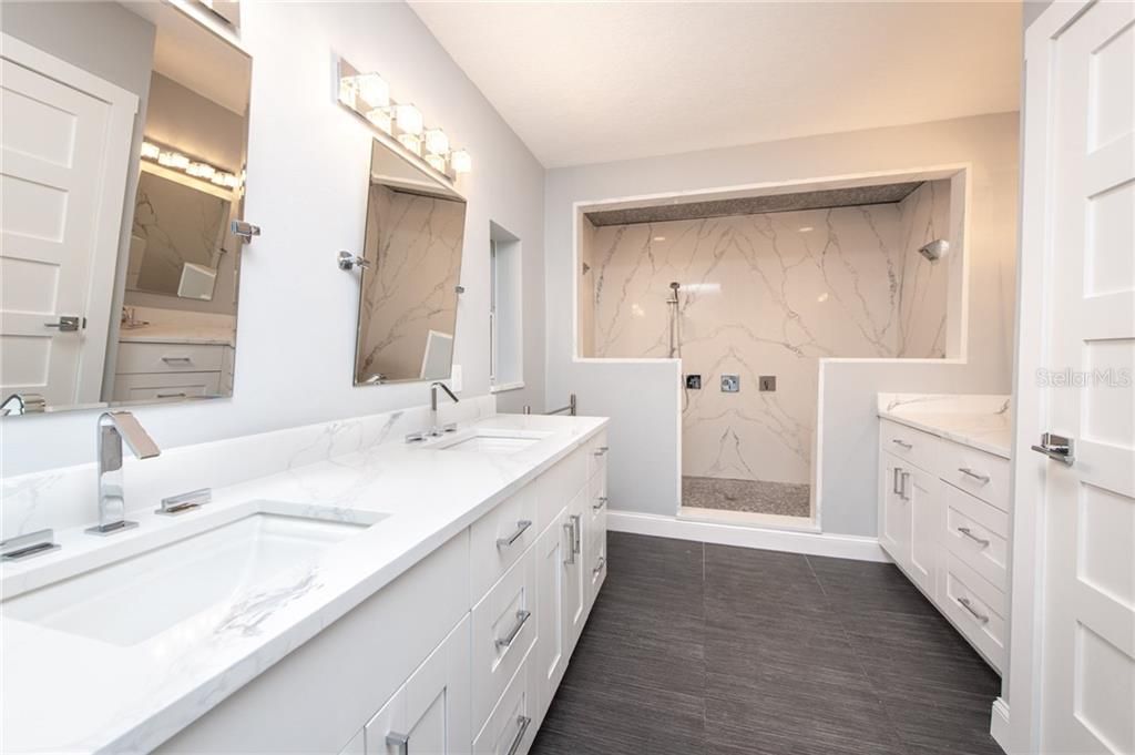 Master bathroom featuring double sinks, a makeup vanity, water closet with bidet, and floor to ceiling quartz slabs in the large shower.