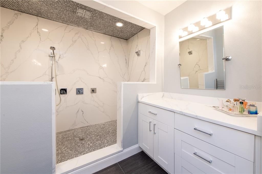 Master bathroom featuring double sinks, a makeup vanity, water closet with bidet, and floor to ceiling quartz slabs in the large shower.