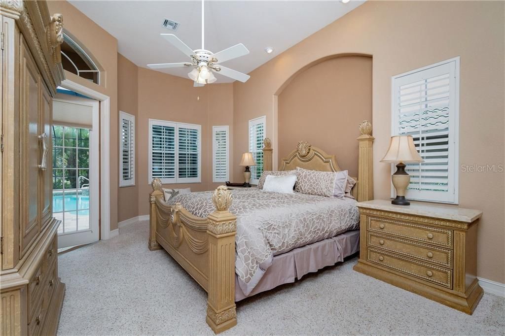 Roomy master suite features plantation shutters and transom window above French doors.