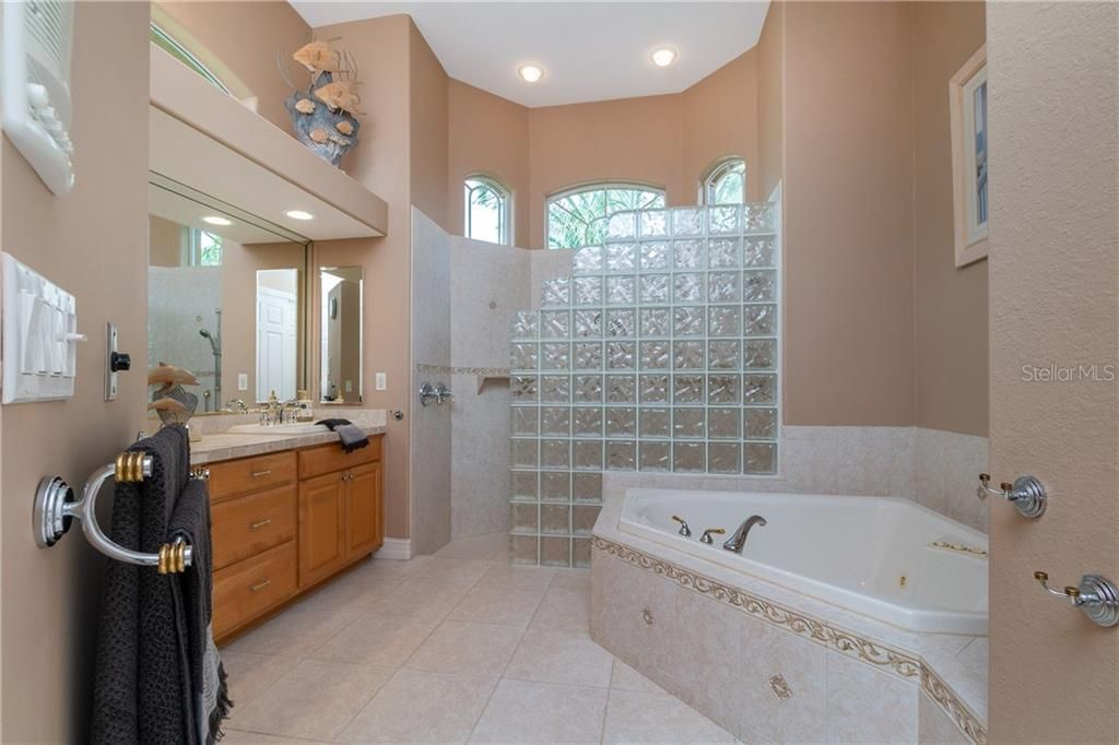 Master bath offers a Roman shower, jetted tub, and vanity with dual sinks.
