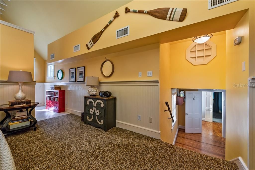 The generously sized PRIMARY BEDROOM boasts VAULTED CEILINGS with BEAMS, WAINSCOTTING as a decorative wall feature, a cozy SEATING AREA and refreshing NATURAL LIGHT!