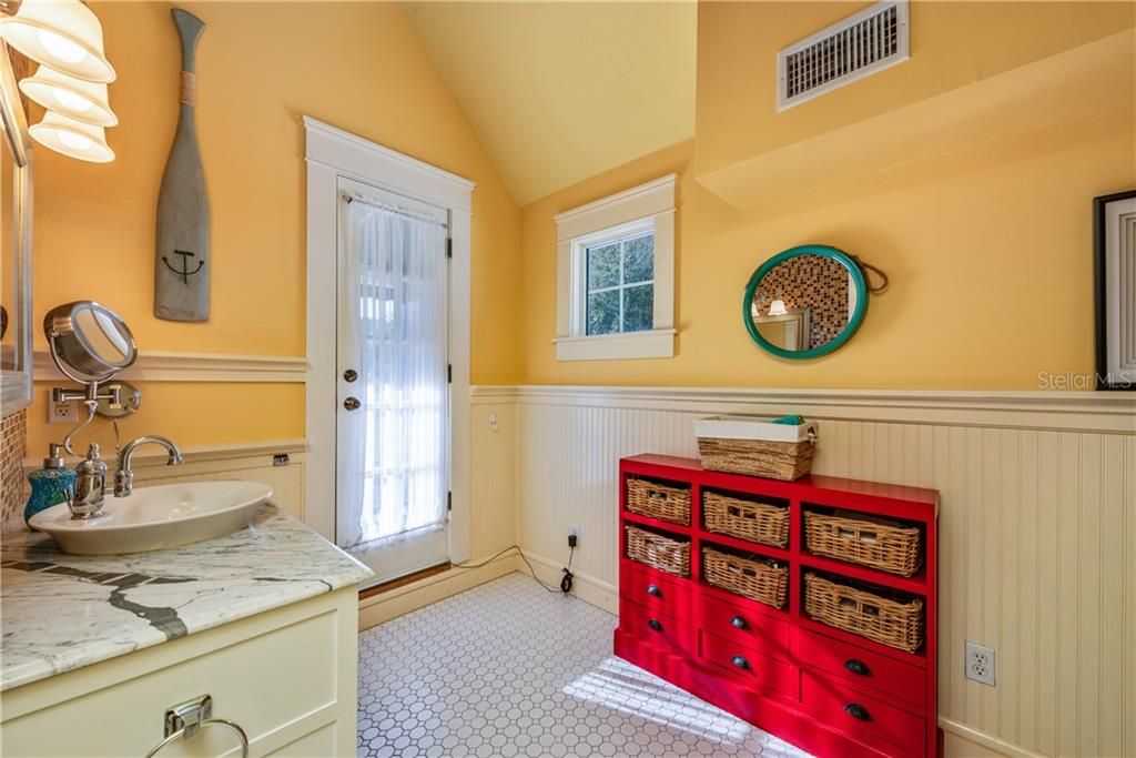 The PRIMARY EN-SUITE BATHROOM offers more WAINSCOTTING, a MARBLE VANITY COUNTERTOP, updated light fixtures, WALK-IN SHOWER & Private Balcony Access!