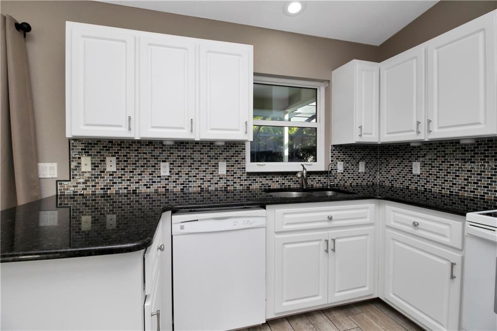 Kitchen features granite counter tops, glass back splash and closet pantry