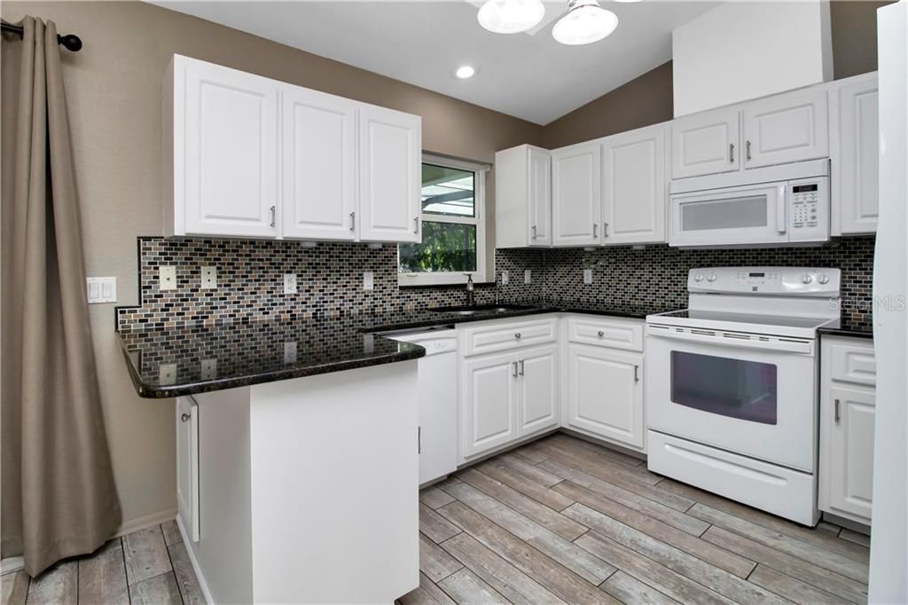 Kitchen features granite counter tops, glass back splash and closet pantry