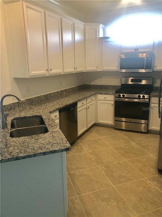 Kitchen with white cabinets and black and grey granite.