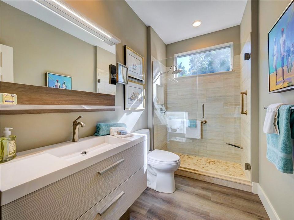 Guest bathroom with custom made vanity, glass shower doors, Toto toilets.