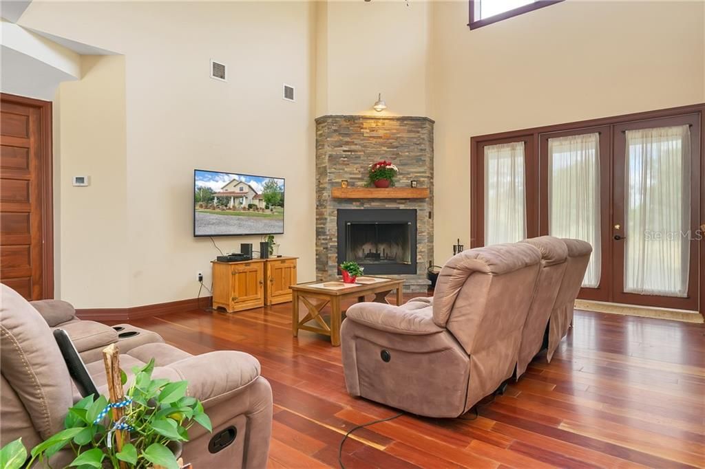 Soaring 2 story great room with stone front wood burning fireplace.  French doors lead out to the covered lanai.   To the right is the kitchen