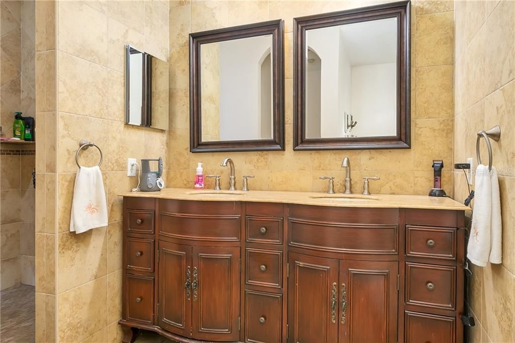 Double master vanity set in furniture piece.  Gleaming tiles and a beautiful place to dress.