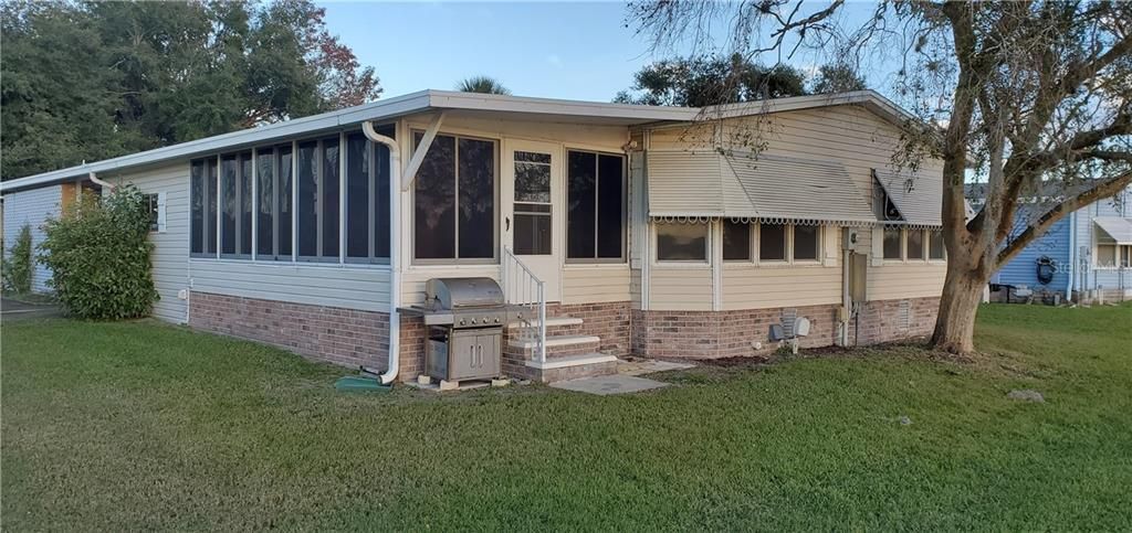 Back of home has a nice shade tree and corner enclosed lanai.