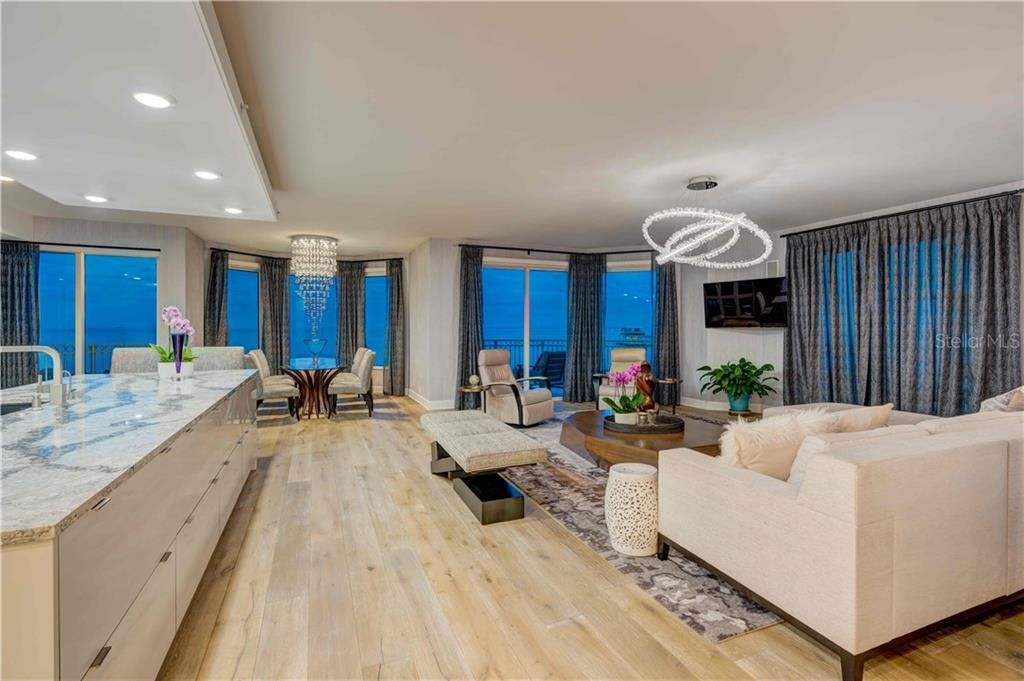 Living room and kitchen island with wide open Tampa Bay views at twilight.