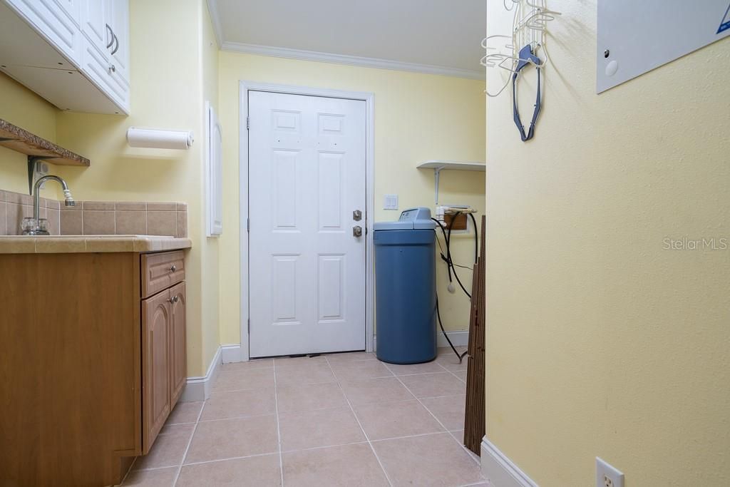 Large laundry room with cabinetry, water, water softener and W/D hookup. Door leads to garage.