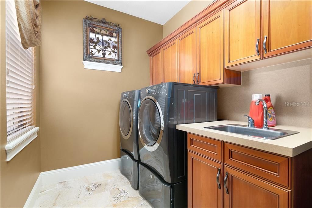 Lovely laundry room with sink & washer & dryer that stay.
