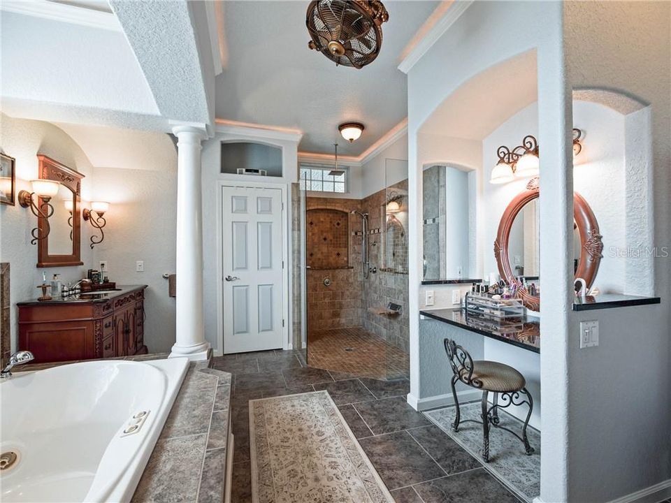 Beautiful Owner's Bath in spacious and features His and Her custom furniture vanities, Her Custom Built-in vanity area with a granite countertop, 360 degree ceiling fan and linen closet.