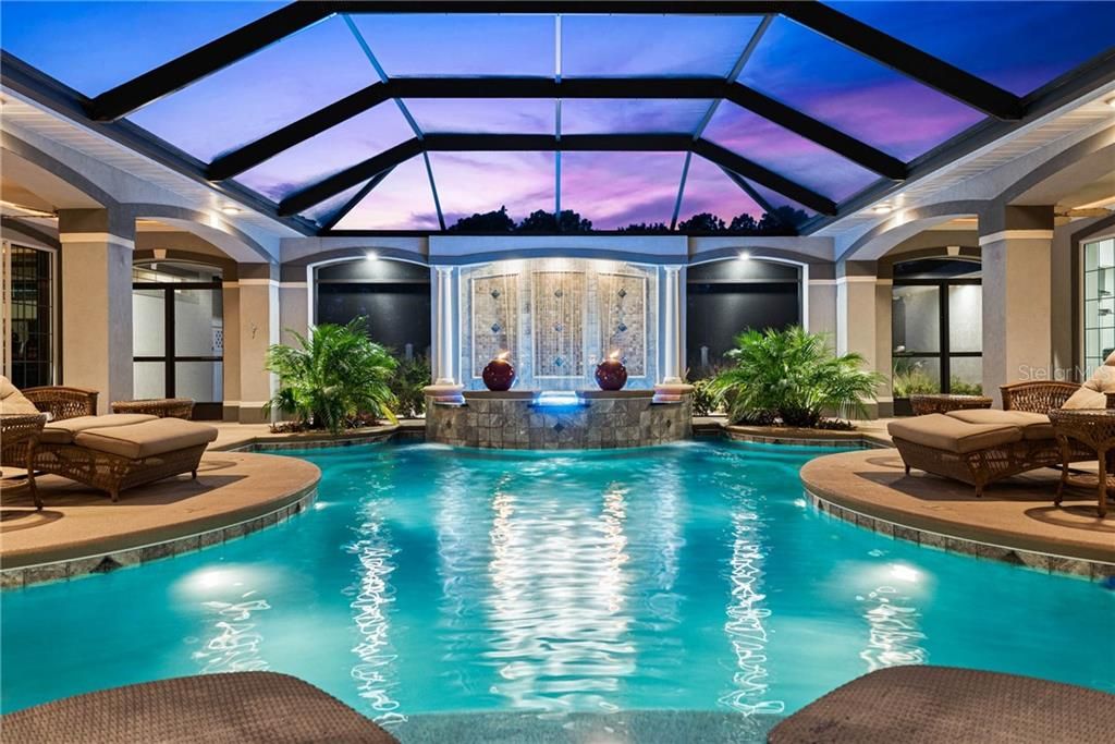 Heated pool with beaching area, planters with topical palms and landscape lighting.