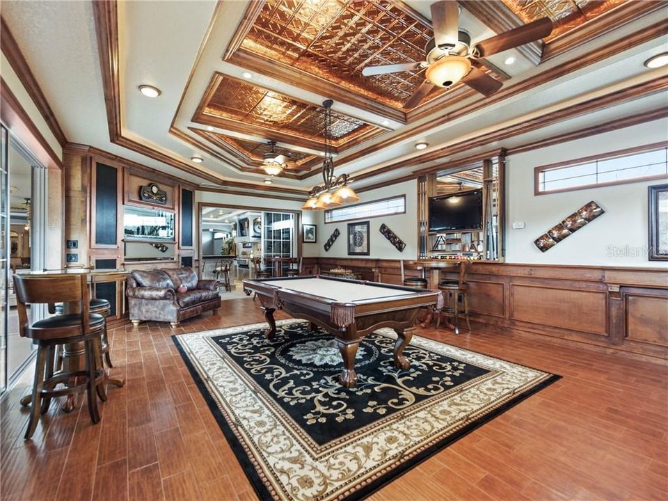 Billiard and Game Room with a view of the 2-sided fish aquarium, handscraped wood-looking tiles and ornate wall and ceiling details grace this amazing space! Everything shown will remain with the home!