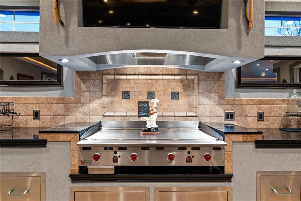 Close up of the Gas Hibachi grill with tiered countertops, stainless steel cabinets and drawers and transom window allowing so much of the natural lighting.