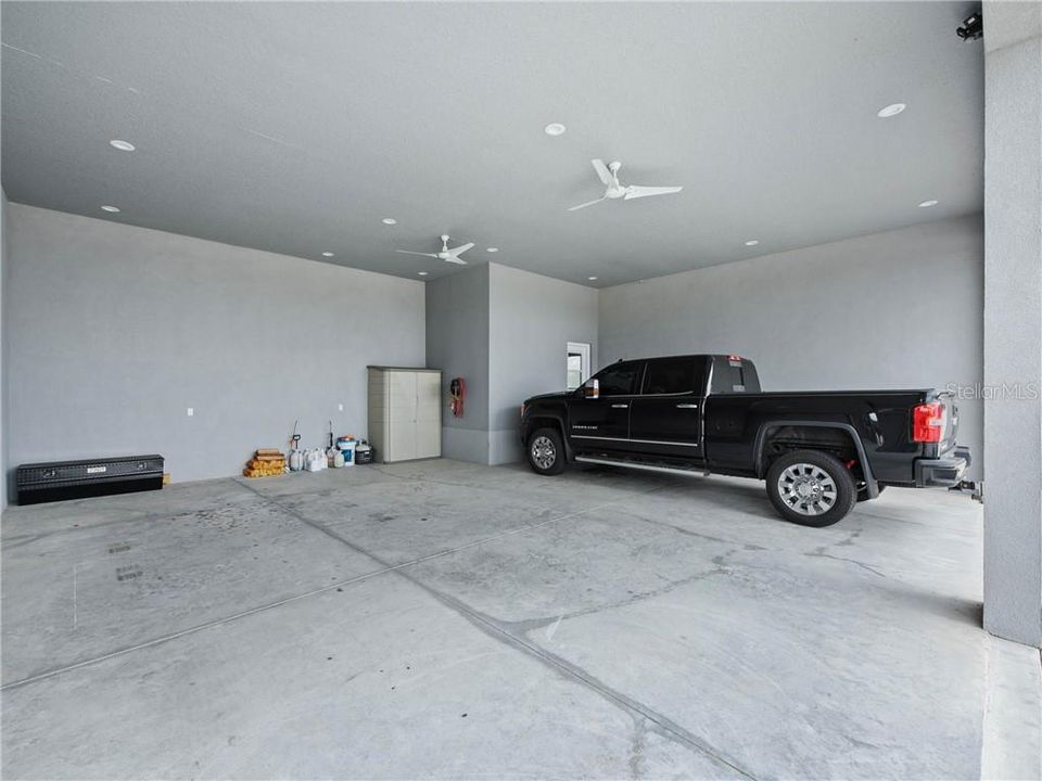 32' wide x approximately 29'-4" oversized 2-bay carport with 12'-6" ceiling heights. Fully equipped with air compressed valve and hoses, turbo ceiling fans, and recess lighting. The door you see to the far right leads into the air-conditioned Dog Suite.