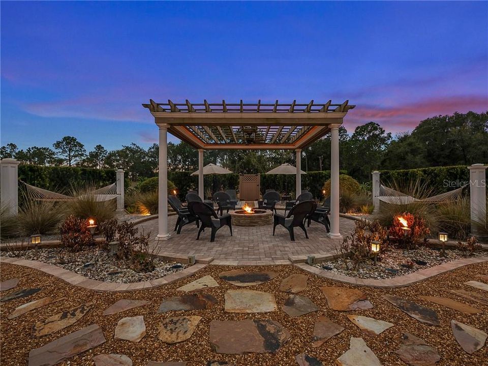 Backyard Pergola with pavers, stacked stone wood burning fire pit, electric and water available. Complete with lounging chairs, two 2-person hammocks and a movie screen.