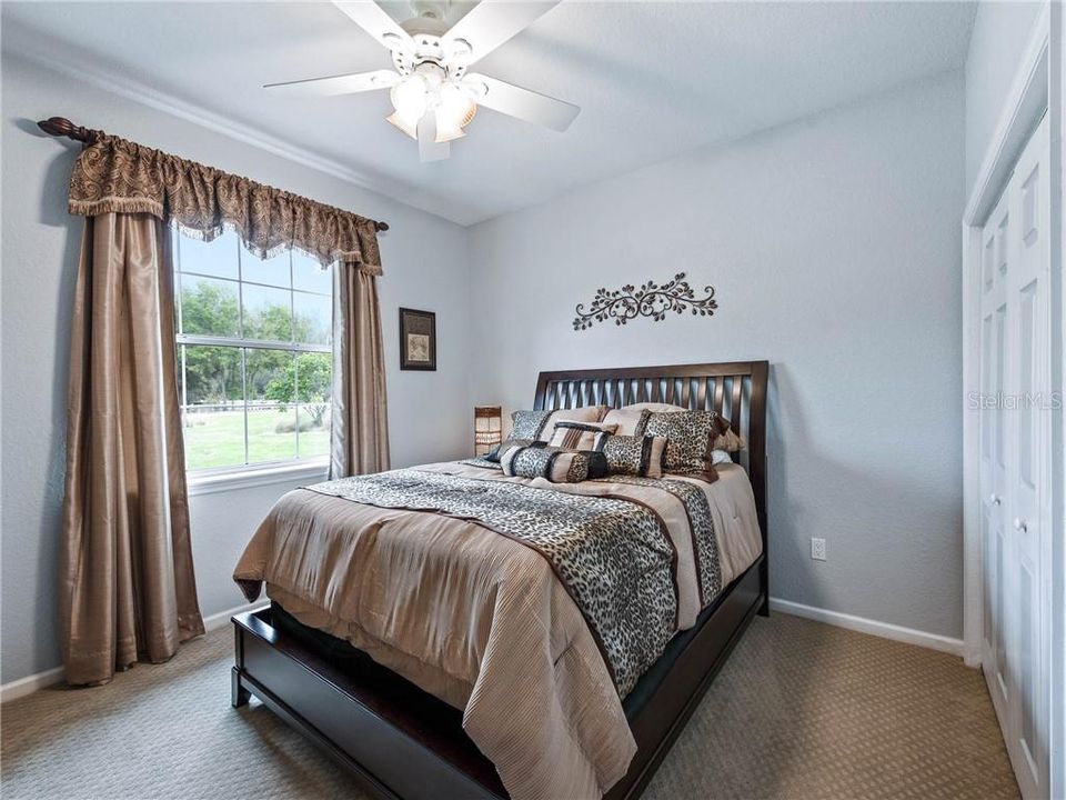 Guest Bedroom #1 with a large window to look out to the Beautiful grounds and 4-Tier fountain that graces the circular driveway. Includes the window treatments, ceiling fan, light and Berber carpeting.