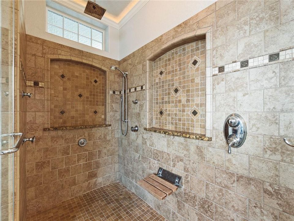 Large Owner shower with His and Her shampoo niches with granite sills, no threshold into the shower, a 4-Function Body spa with a rain shower head and a shower seat. The glass block window above allows so much of the natural lighting into this beautiful space.